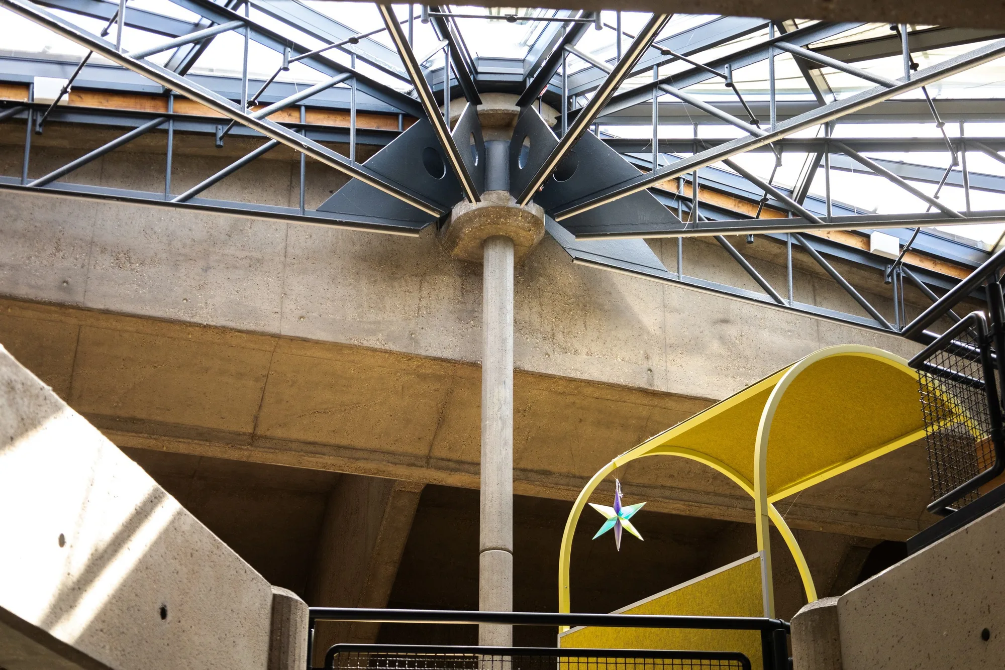 Concrete column and glass roof above the open learning area, with a yellow arched seating niche