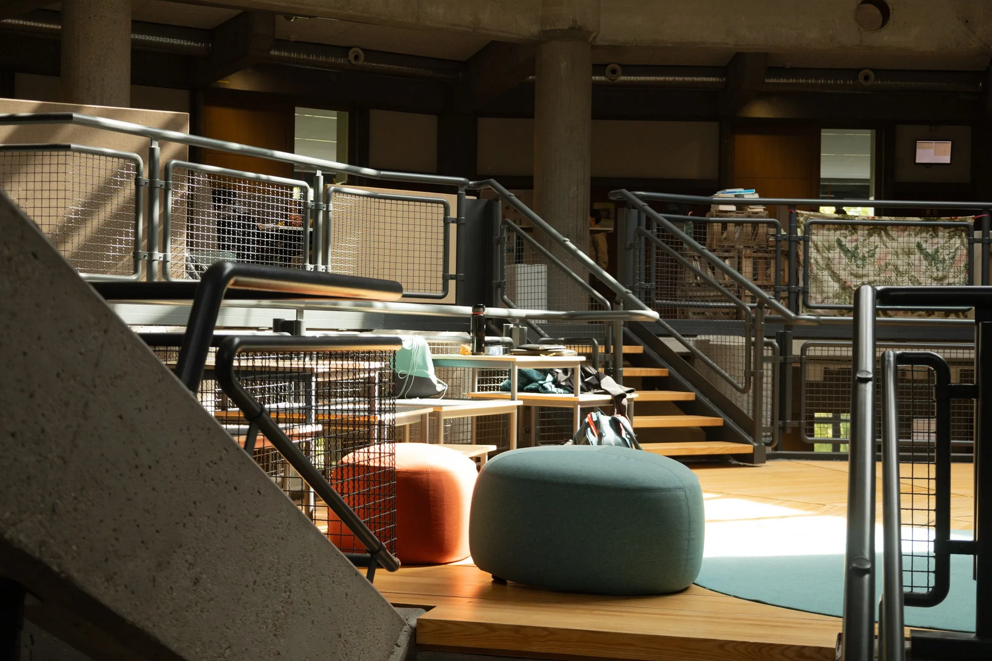 Open learning area at Theresianum Mainz: wooden steps, railings and seating poufs on several levels