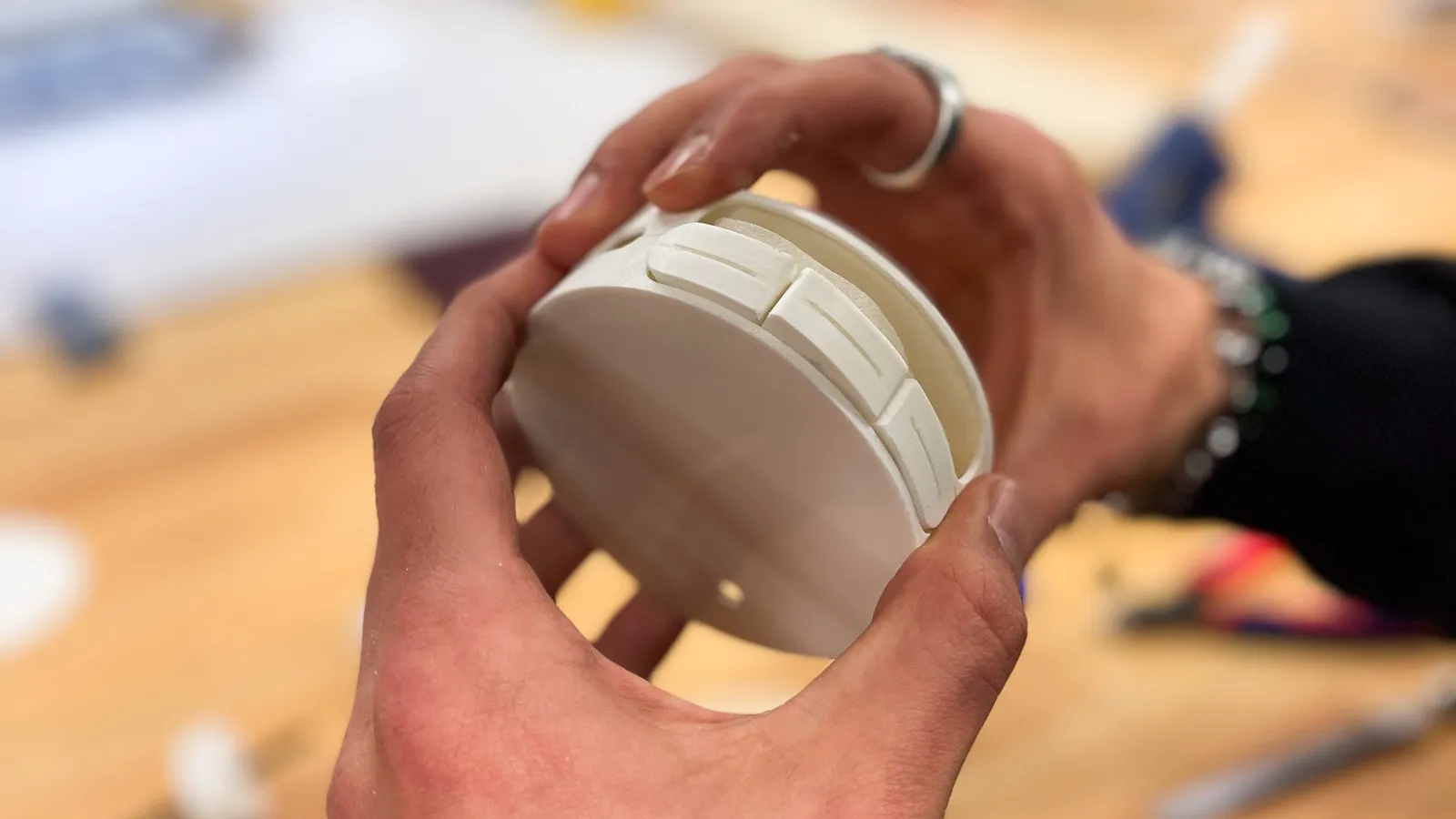 Two hands holding a white printed model of Senzu